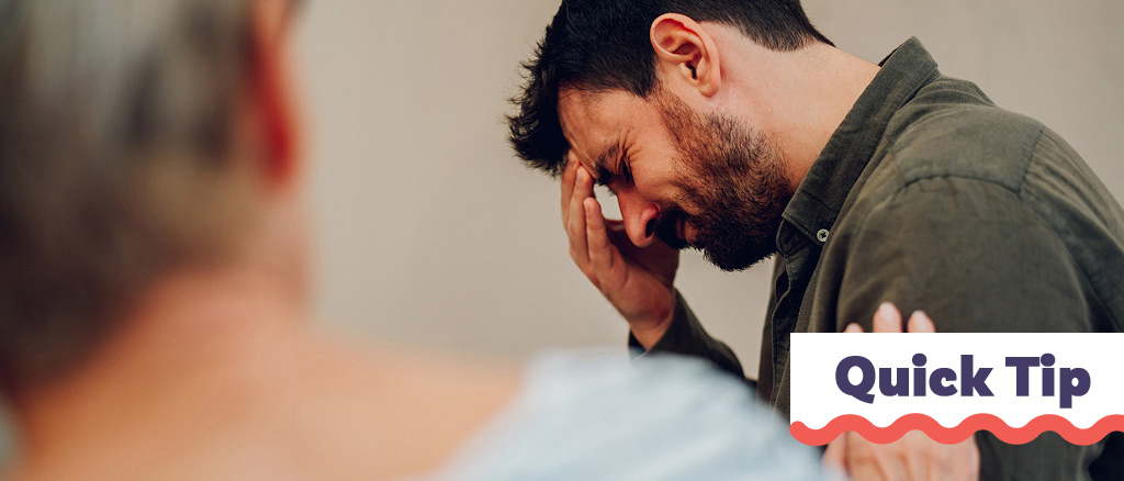Un homme montre de l'émotion ou de la douleur tandis qu'une femme le soutient. 